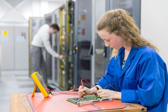 Young engineering apprentice working on a circuit board © BAE Systems