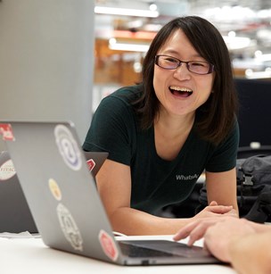 Female engineer, East Asian, wearing glasses and laughing