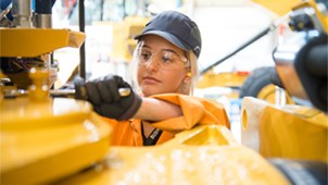 Engineering Technician at work; woman, wearing safety goggles, gloves and a baseball cap.