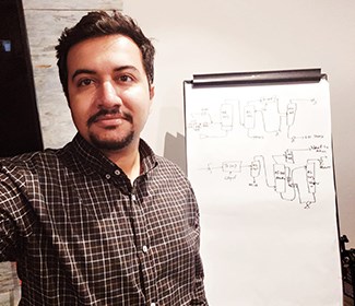 A man stands in front of a flip chart with a diagram drawn on it.