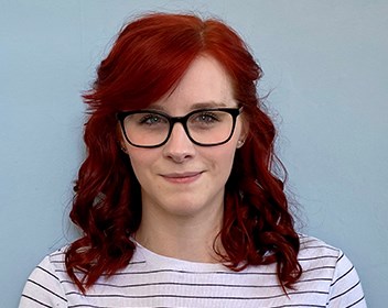 Female person with red curly hair and glasses