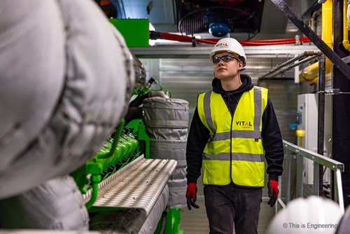 Male apprentice engineer inspecting a combined heat and power engine