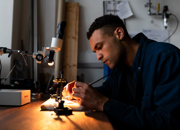 Male mechanical engineer solders parts for prosthetic limbs